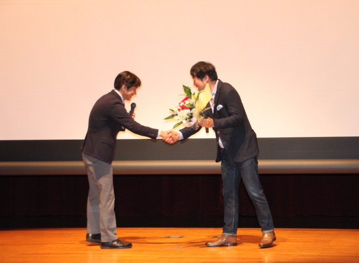 花束贈呈後、握手を交わす二人（左：町長、右：監督）